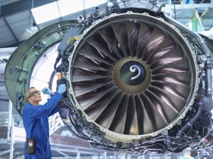 Engineers working on aircraft engine in aircraft maintenance factory